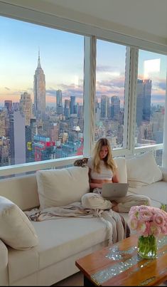 a woman sitting on top of a couch in front of a window