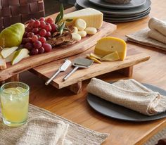 an assortment of cheeses and fruit on a wooden platter next to wine glasses