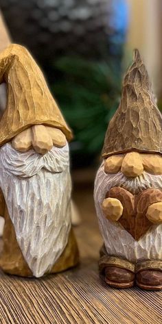 two gnome figurines sitting next to each other on top of a wooden table