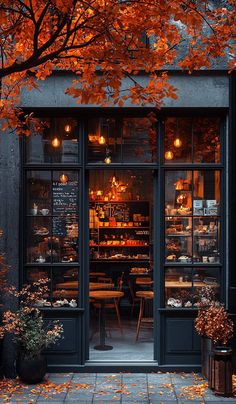 an outside view of a restaurant with autumn leaves on the ground and tables in front