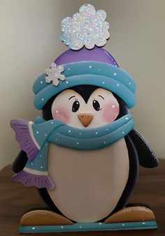 a penguin figurine wearing a blue hat and scarf with snowflakes on its head