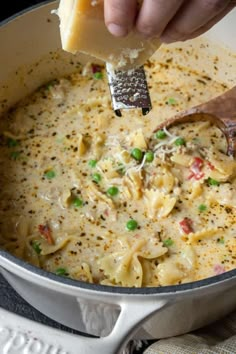 a person scooping cheese out of a pot filled with pasta