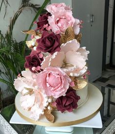 a wedding cake decorated with pink and burgundy flowers