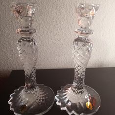 two glass candlesticks sitting on top of a table