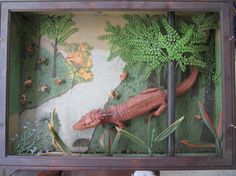 a wooden box with fake alligators and plants in it