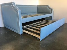 a blue bed frame with drawers underneath it