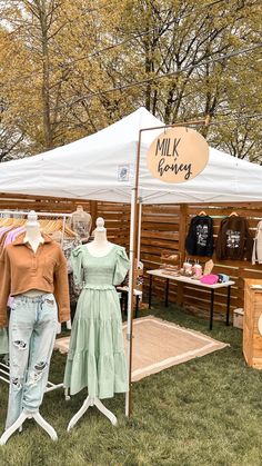 two mannequins in front of a white tent with milk clothing on display