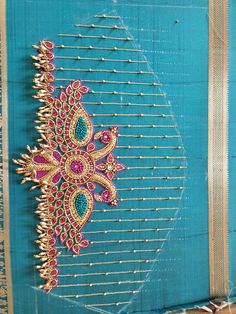 an intricately designed hair comb is displayed on a piece of blue fabric with gold trim