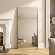 a large mirror sitting on top of a wooden floor next to a fireplace in a living room