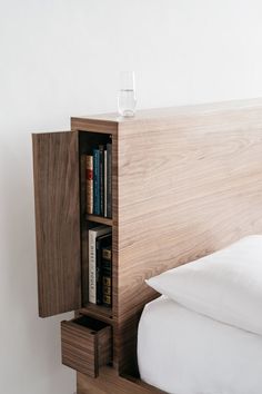 a bed with a book shelf next to it and a glass sitting on top of it