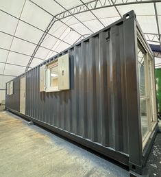 a large gray container sitting inside of a building next to a white roof and windows