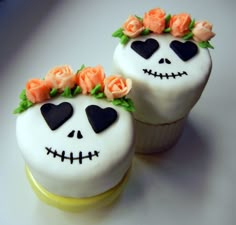 two cupcakes decorated with white frosting and orange roses are sitting next to each other