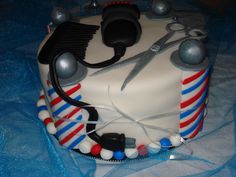 a cake decorated with scissors and beads on a blue tableclothed cloth, ready to be cut