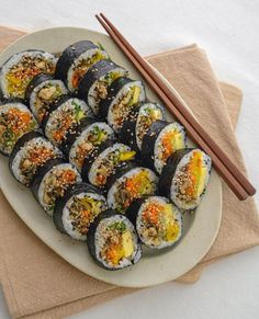 a plate full of sushi with chopsticks next to it on a table