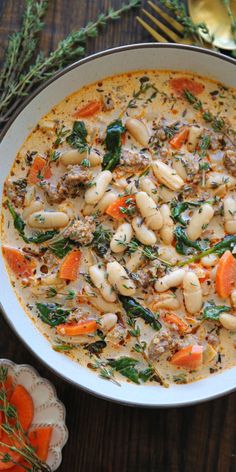 a bowl of soup with carrots, spinach and other vegetables on the side