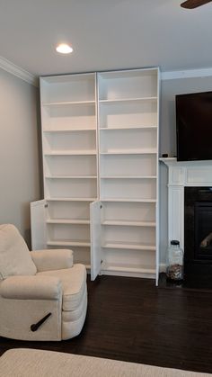 a living room with white bookcases and a tv on the wall above a fireplace