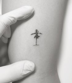 a person with a tattoo on their arm is holding up a small stick and arrow