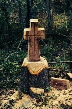 a wooden cross sitting in the middle of a forest