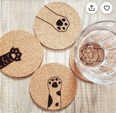 four cork coasters with designs on them and a glass bowl in the middle, sitting on a wooden table