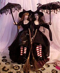 two dolls dressed in black with red striped socks and holding umbrellas on a white background