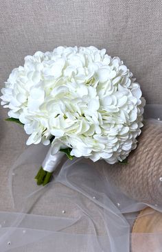 a bridal bouquet is sitting on a couch with white flowers in the middle of it