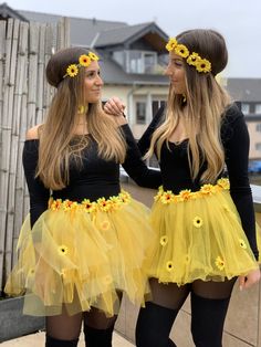 two beautiful young women standing next to each other wearing sunflower skirts and headbands