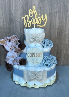 a teddy bear sitting on top of a blue and white diaper cake