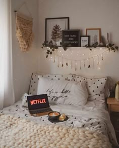 a laptop computer sitting on top of a bed in a bedroom next to pillows and blankets