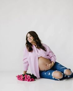 a pregnant woman sitting on the floor with flowers