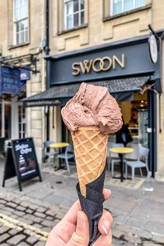 someone holding up an ice cream cone in front of a building