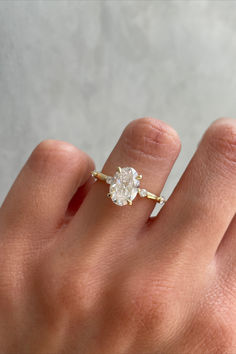 a woman's hand with a diamond ring on top of her finger and the other hand holding an engagement ring