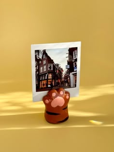 an animal paw is placed on top of a small photo frame in the shape of a bear's paw