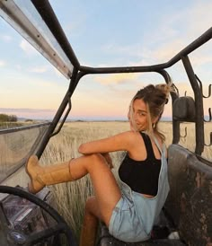 a woman sitting in the driver's seat of a truck with her legs crossed