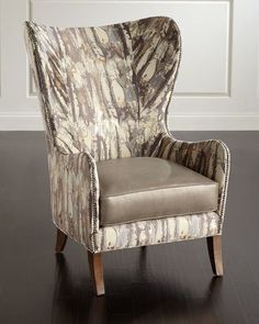 an upholstered chair sits in front of a white paneled wall and hardwood floor