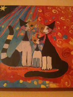 two cats sitting next to each other on a painting