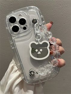 a person holding up a clear phone case with a cat keychain attached to it