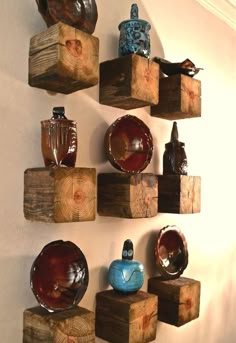 several pieces of wood are arranged on the wall with bowls and vases in them