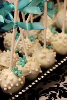 cake pops with blue and white decorations on a black platter at a wedding reception