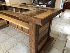 a kitchen island made out of pallets and wooden planks, in the middle of a tile floor