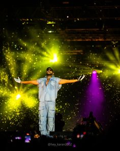 a man standing on top of a stage holding his arms out in front of the crowd