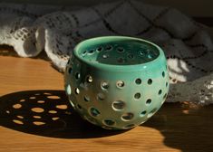 a green vase sitting on top of a wooden table next to a white doily