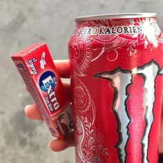 a person holding up a can of soda and a tube of toothpaste in their hand