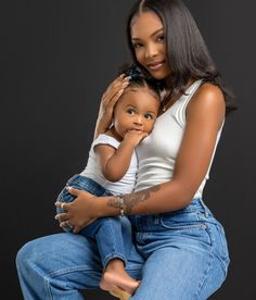 a woman holding a child in her lap and posing for the camera with black background