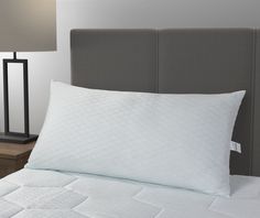 a close up of a bed with white pillows and a night stand in the background