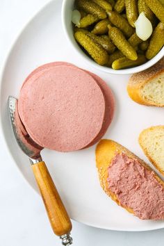 a white plate topped with bread and pickles next to a bowl of pickles