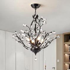 a chandelier hanging from the ceiling in a room with white walls and cabinets