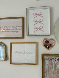 there are many framed pictures on the wall with pink and white ribbons hanging above them