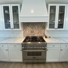 a stove top oven sitting inside of a kitchen next to white cabinets and counter tops