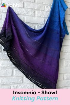 a purple and blue shawl hanging on a brick wall