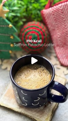 a cup of coffee sitting on top of a wooden coaster next to a christmas tree